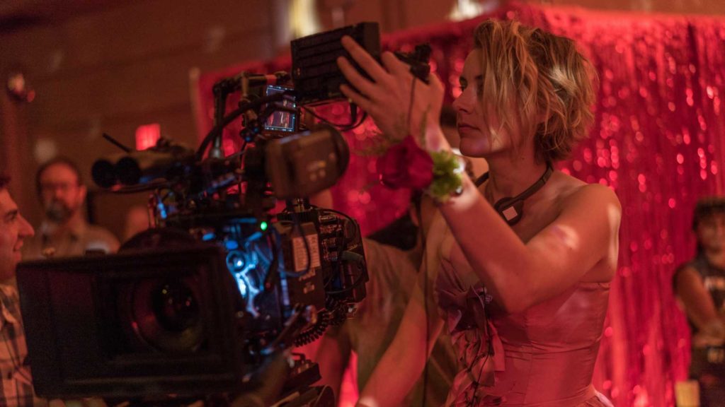 An image of Greta Gerwig looking at a camera monitor taking a hands-on approach perfectly demonstrating how to direct a movie like Greta Gerwig